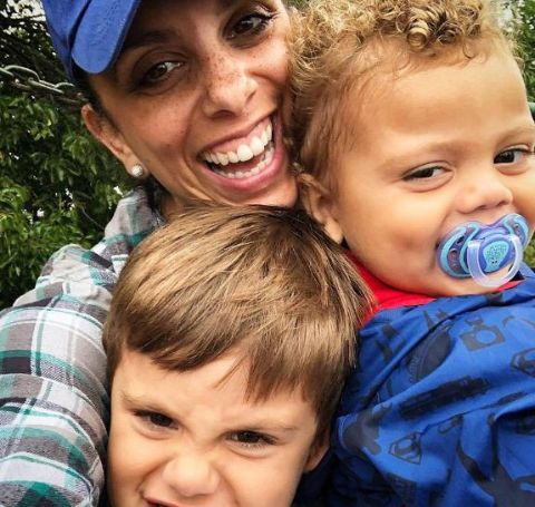 Jaryn Arnold Rothman wearing a blue cap and shirt clicks a selfie with her two sons who are smiling.
