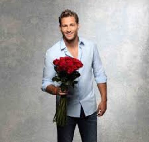 Juan Pablo Galavis in a grey shirt poses with a roses.