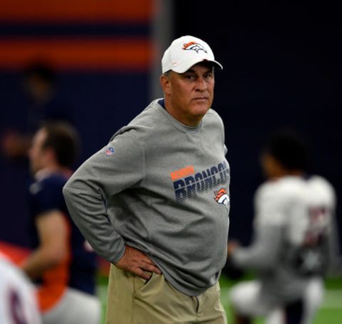 Vic Fangio looks at the game from sidelines in Denver Broncos's grey t-shirt.