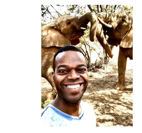 Demore Barnes in a white t-shirt poses in front of animals.