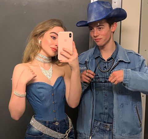 Griffin Gluck in a blue shirt and hat poses with his girlfriend Sabrina Carpenter.