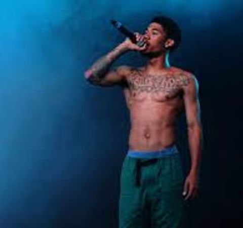 Rapper Hodgy singing at a concert topless.