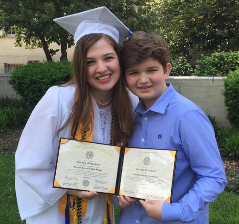 Alexa Schiff in a graduation down poses with her little brother.