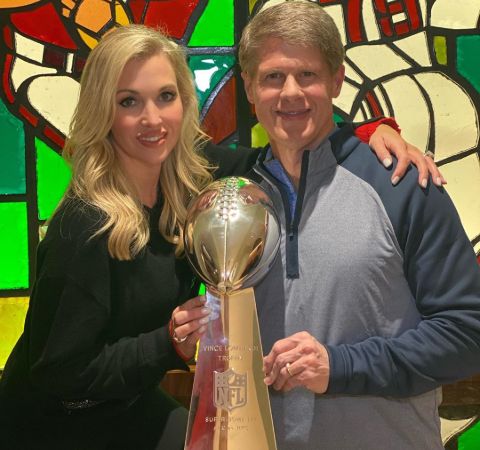 Tavia Hunt in a black dress poses with the super bowl trophy with husband Clark Hunt.
