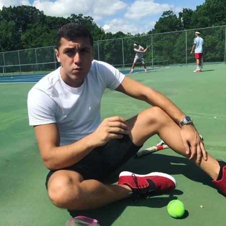 Isaac Nakash poses in a tennis court.