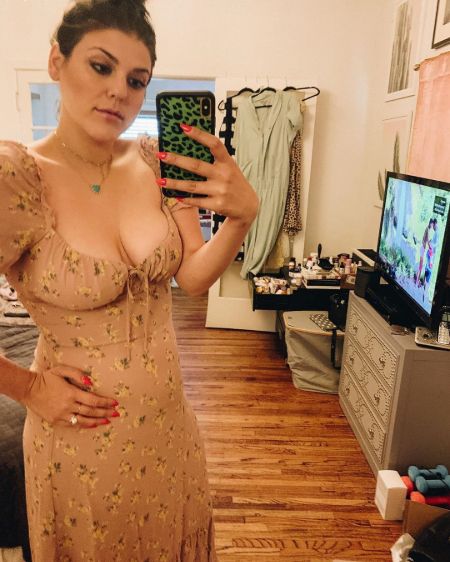 Molly Tarlov in a skin coloured dress poses for a selfie.