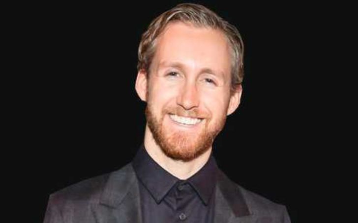Adam Shulman wearing a black suit and smiling